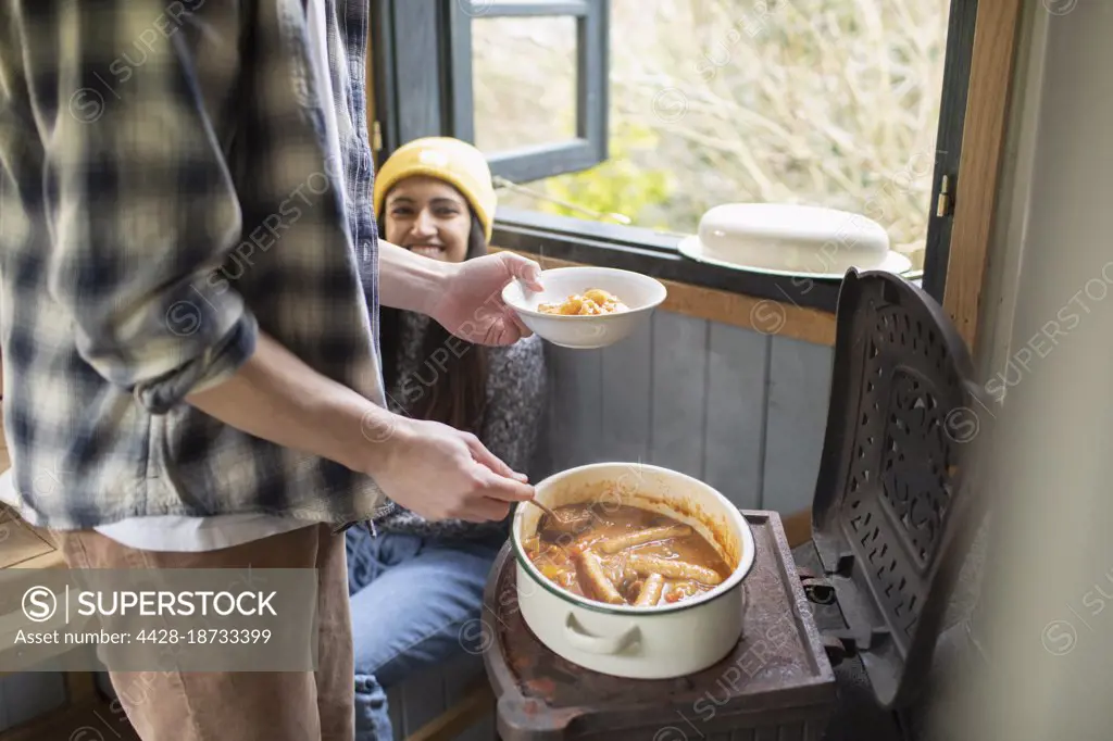Happy young couple making stew in tiny cabin rental