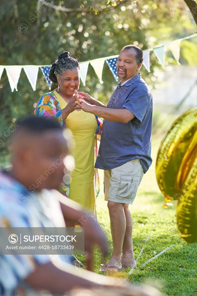Happy mature couple dancing in summer backyard