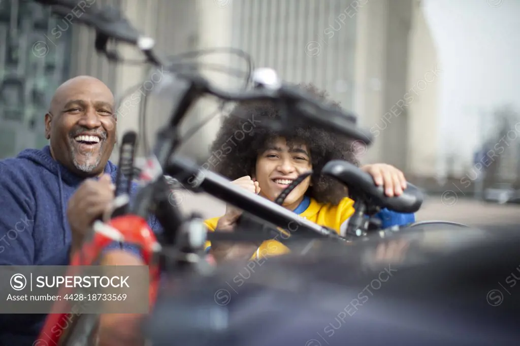 Portrait happy father and son with. bicycles on urban sidewalk