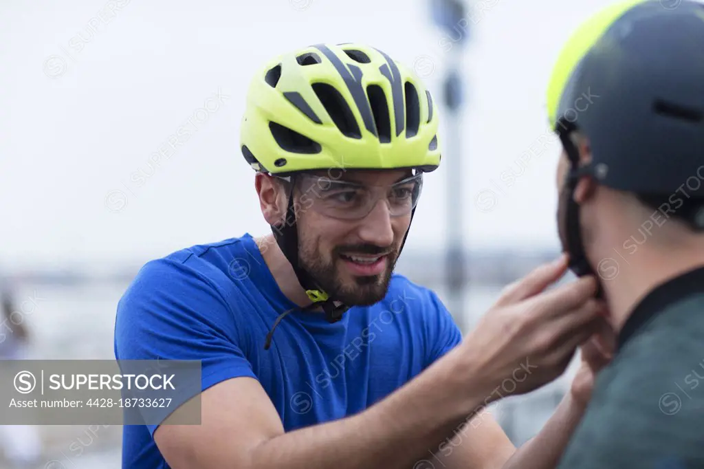 Man helping friend with bike helmet