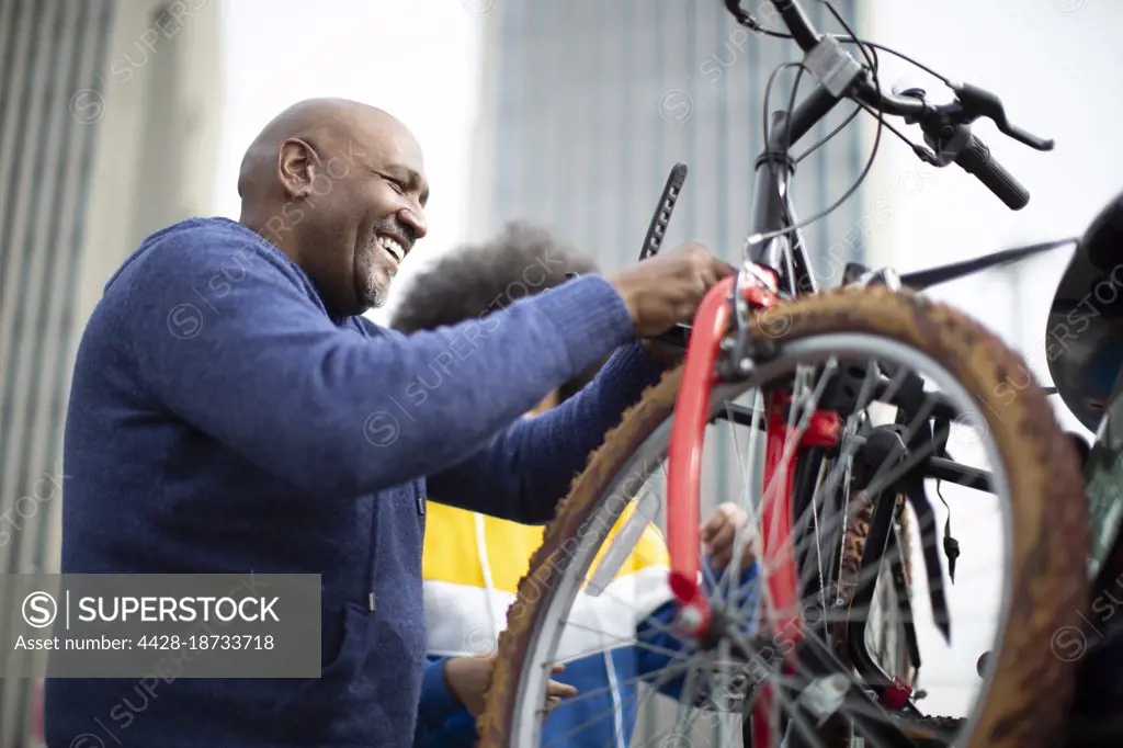 Happy man placing. bicycle on car bike rack in city