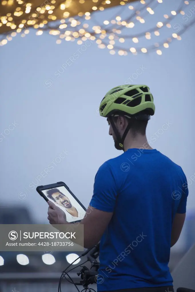 Man in bike helmet video chatting with friend on digital tablet screen