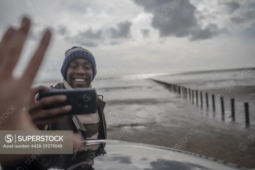 Happy man with camera phone on winter beach