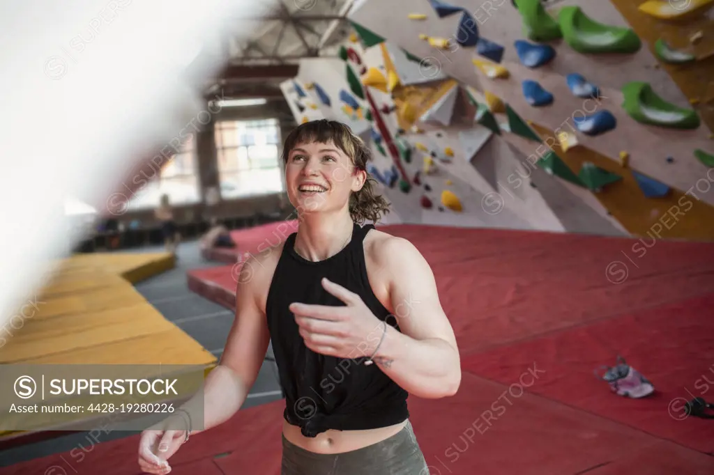 Happy young female rock climber in climbing gym