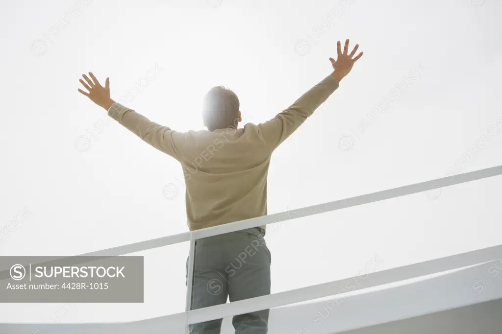 Spain, Sun shining behind businessman with arms raised