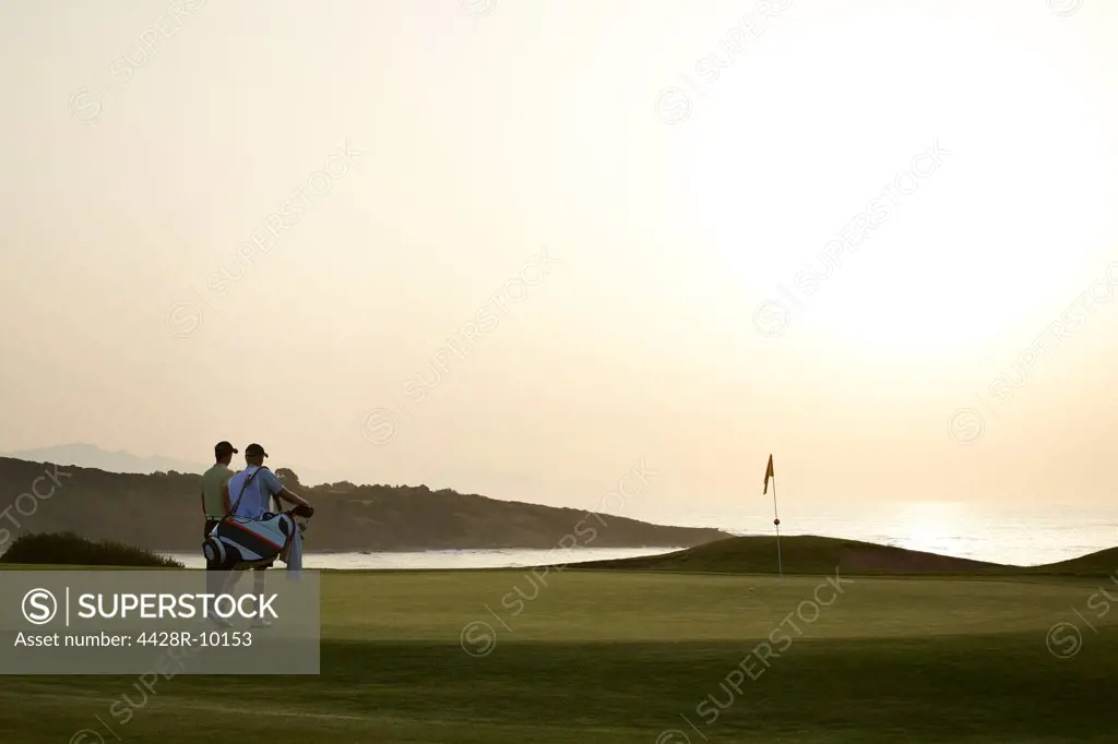 Men on golf course at sunset