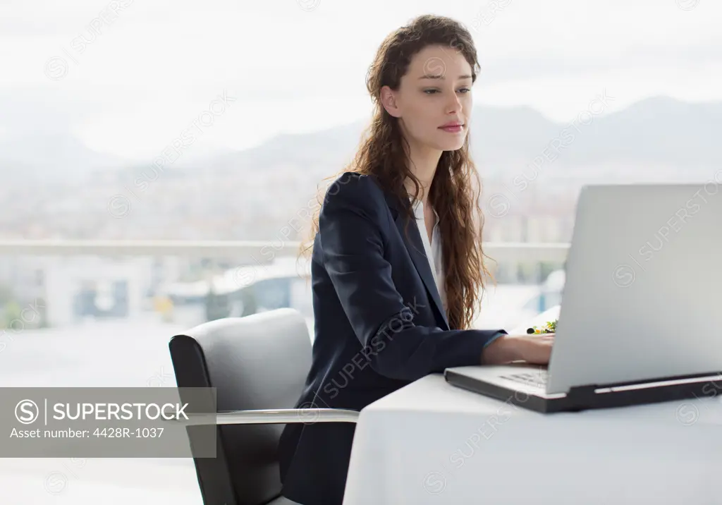 Spain, Businesswoman using laptop in office