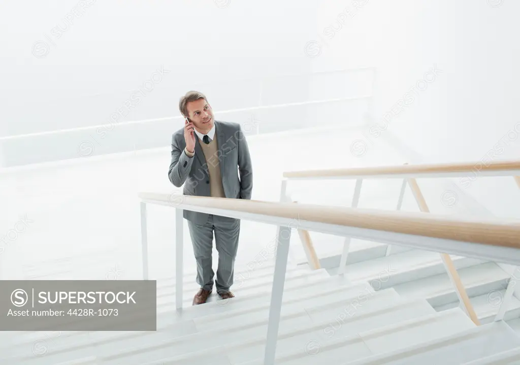 Spain, Businessman talking on cell phone at base of stairs