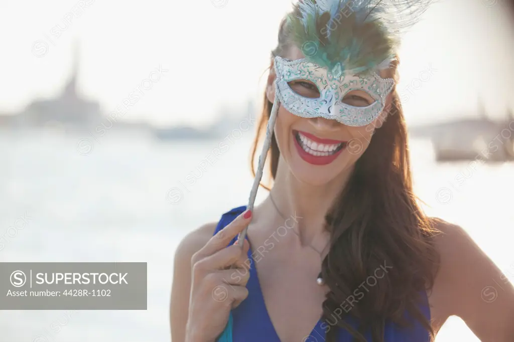Venice, Portrait of smiling woman wearing mask at waterfront in Venice