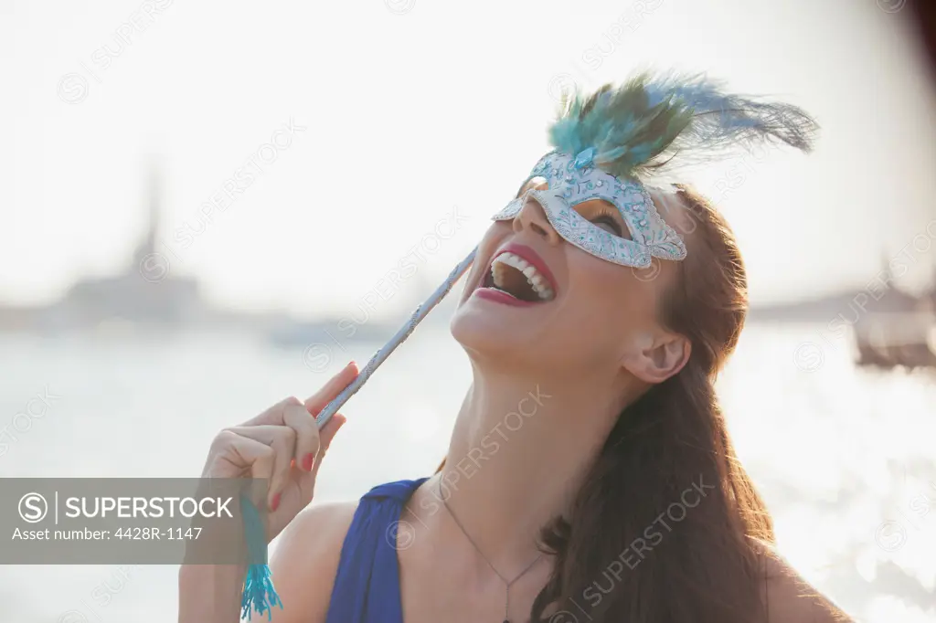 Venice, Laughing woman with mask at waterfront in Venice