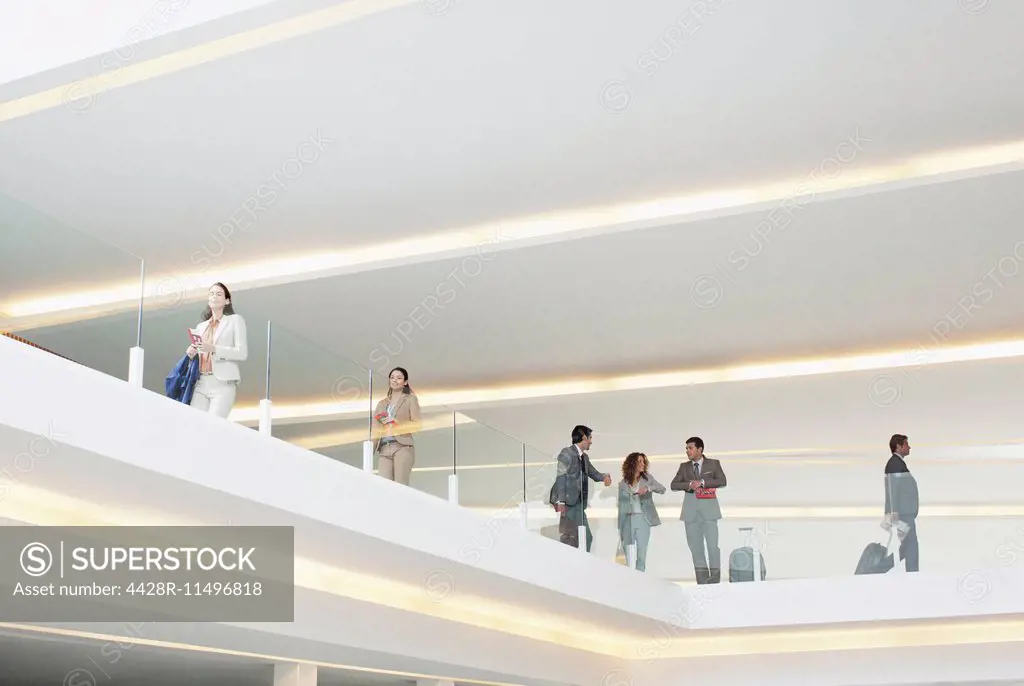 Business people leaning on glass railing of elevated walkway