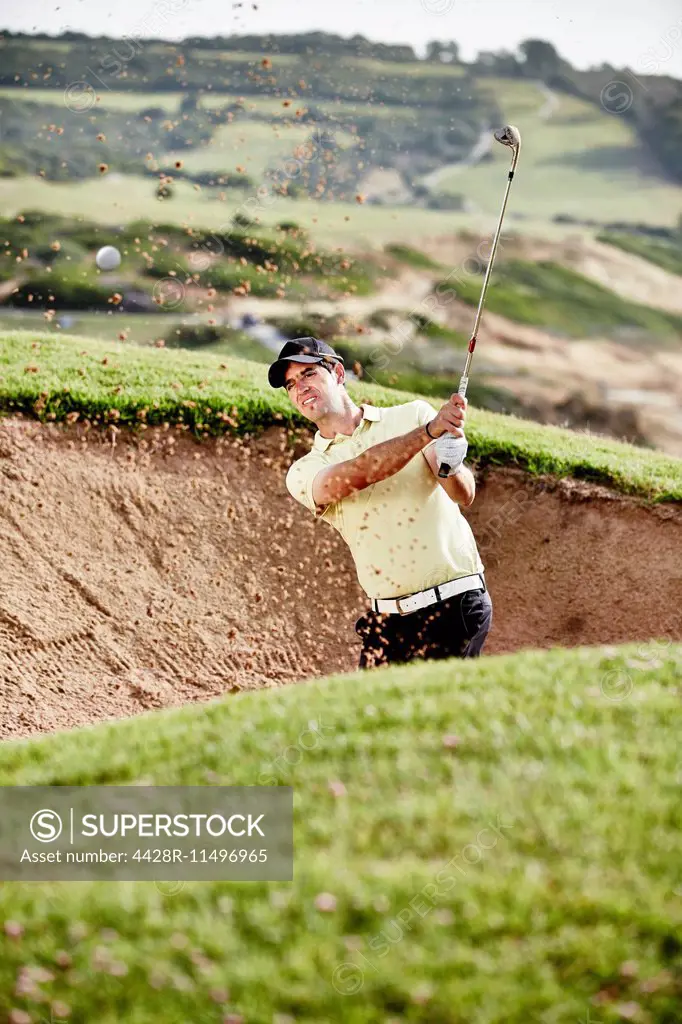 Man swinging from sand trap on golf course