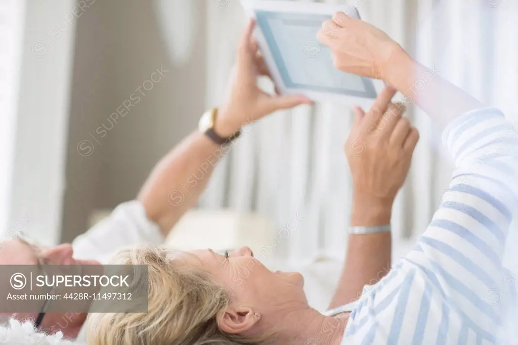 Older couple using digital tablet on bed