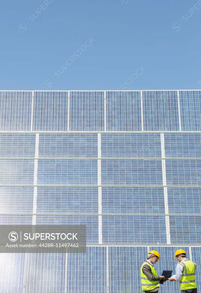 Workers examining solar panels in rural landscape