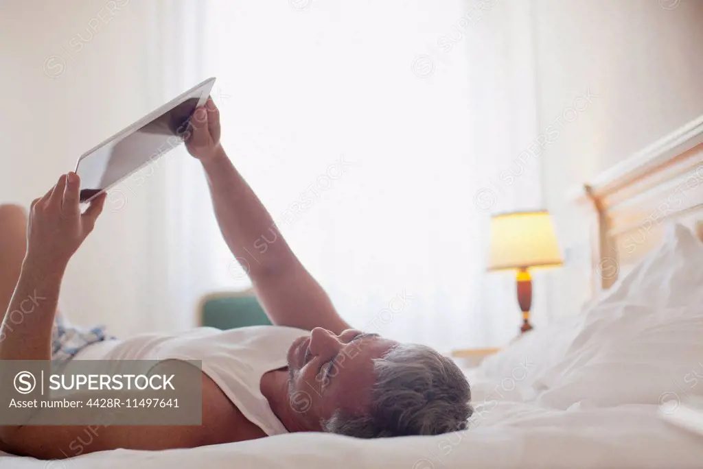 Man laying in bed and using digital tablet