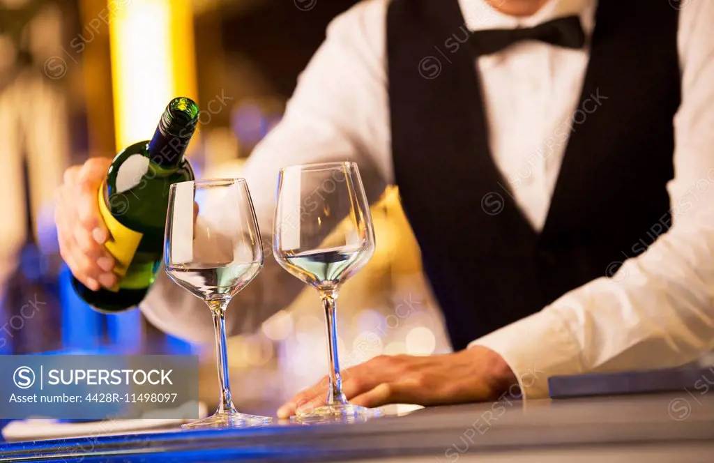 Well dressed bartender pouring wine