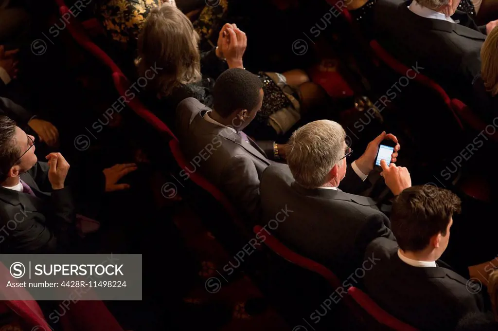 Man using cell phone in theater audience