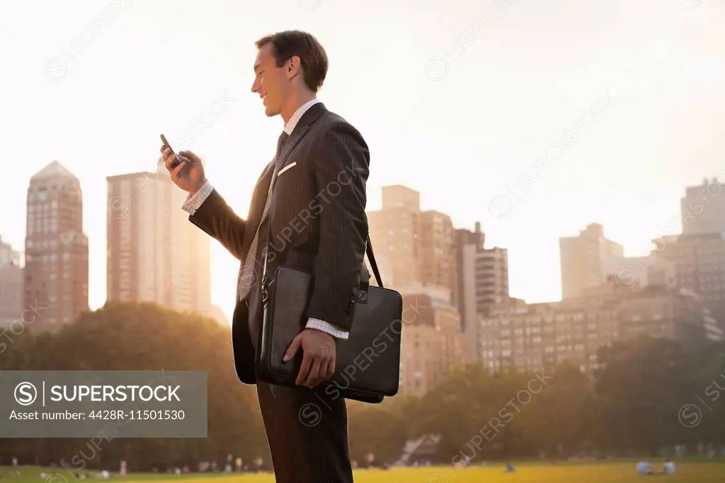Businessman using cell phone in urban park