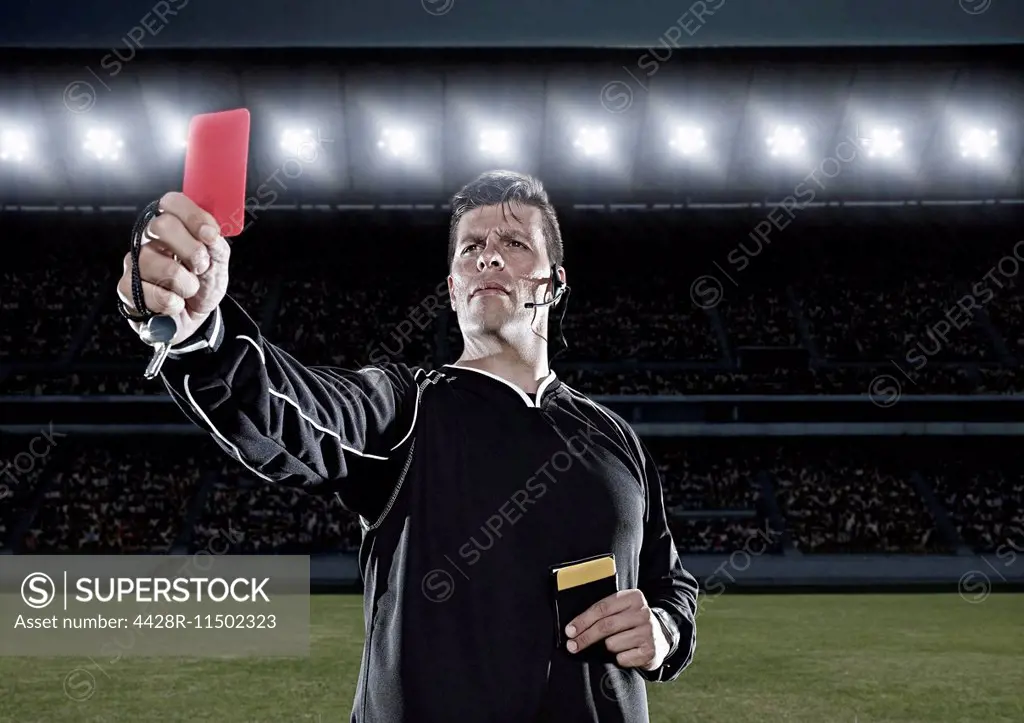 Referee flashing red card on soccer field
