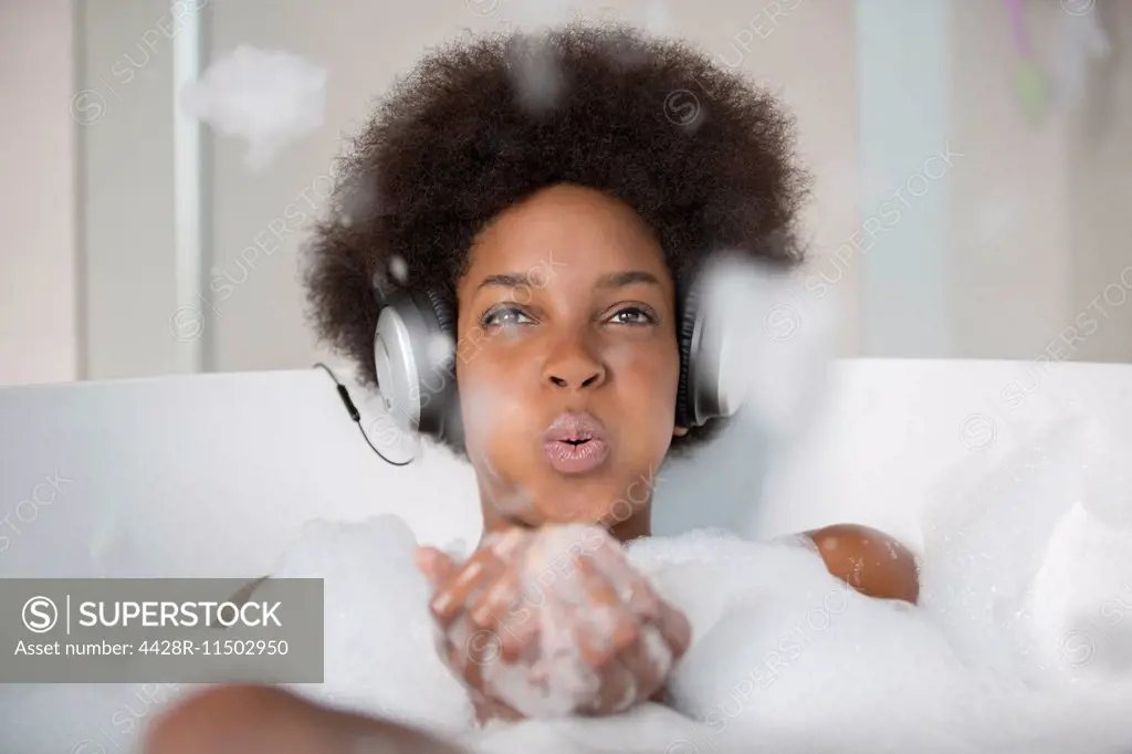 Woman listening to headphones in bath