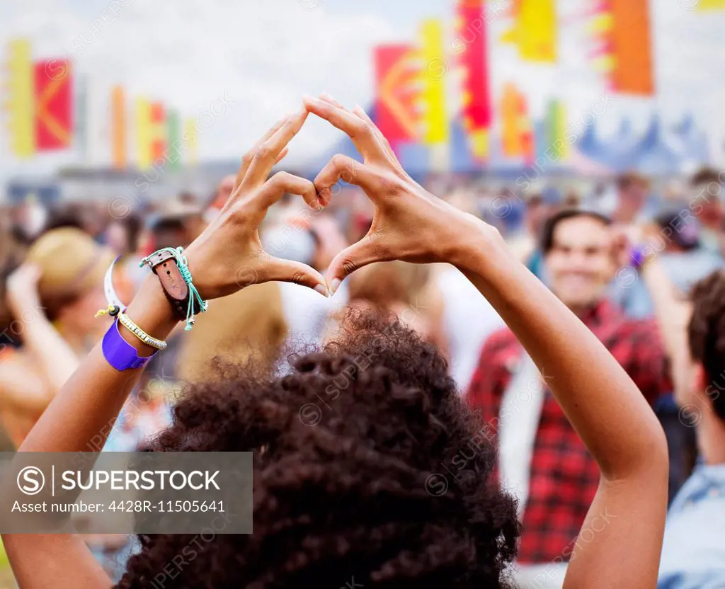 Woman forming heart-shape with hands at music festival