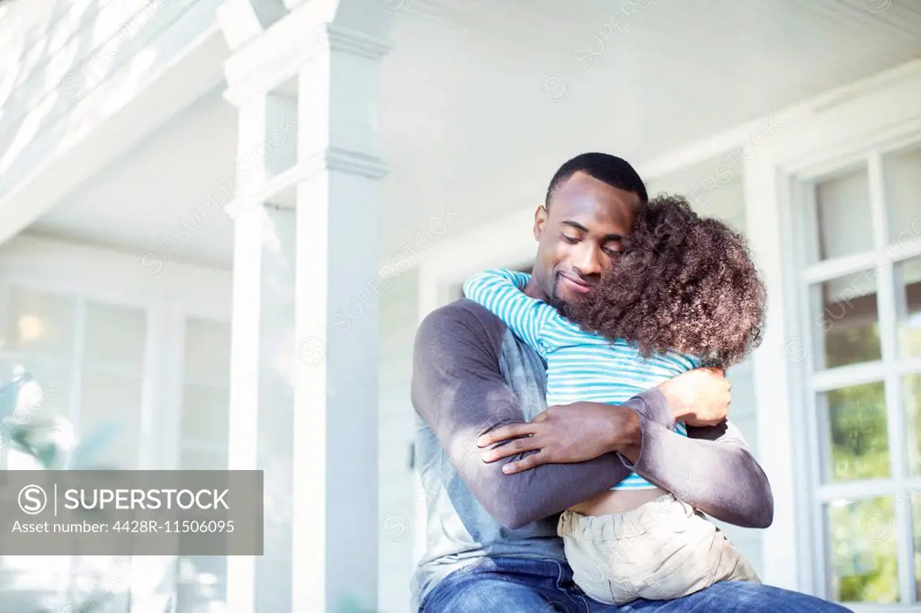 Father hugging daughter on porch