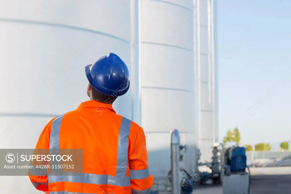 Worker looking up at silage storage towers