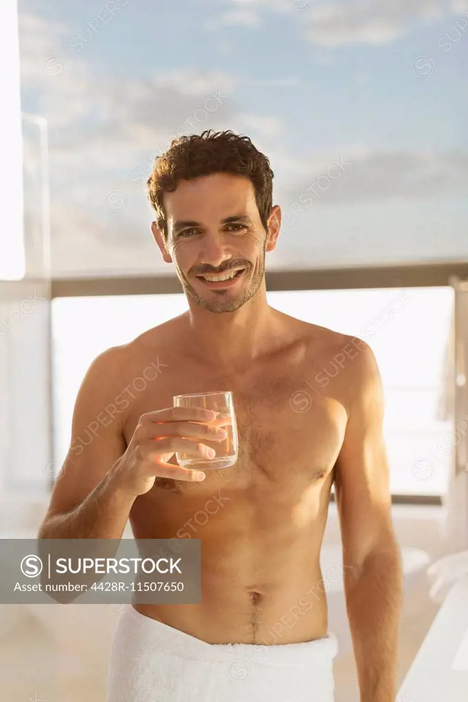 Portrait of smiling man drinking water in bathroom