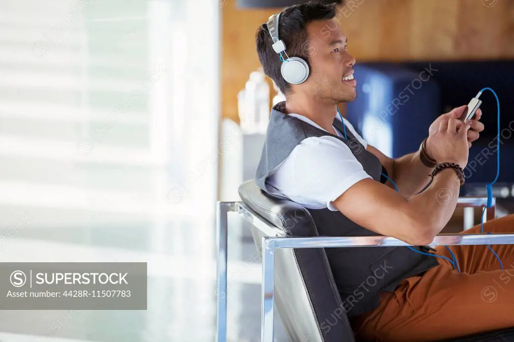 Smiling businessman listening to music on mp3 player with headphones