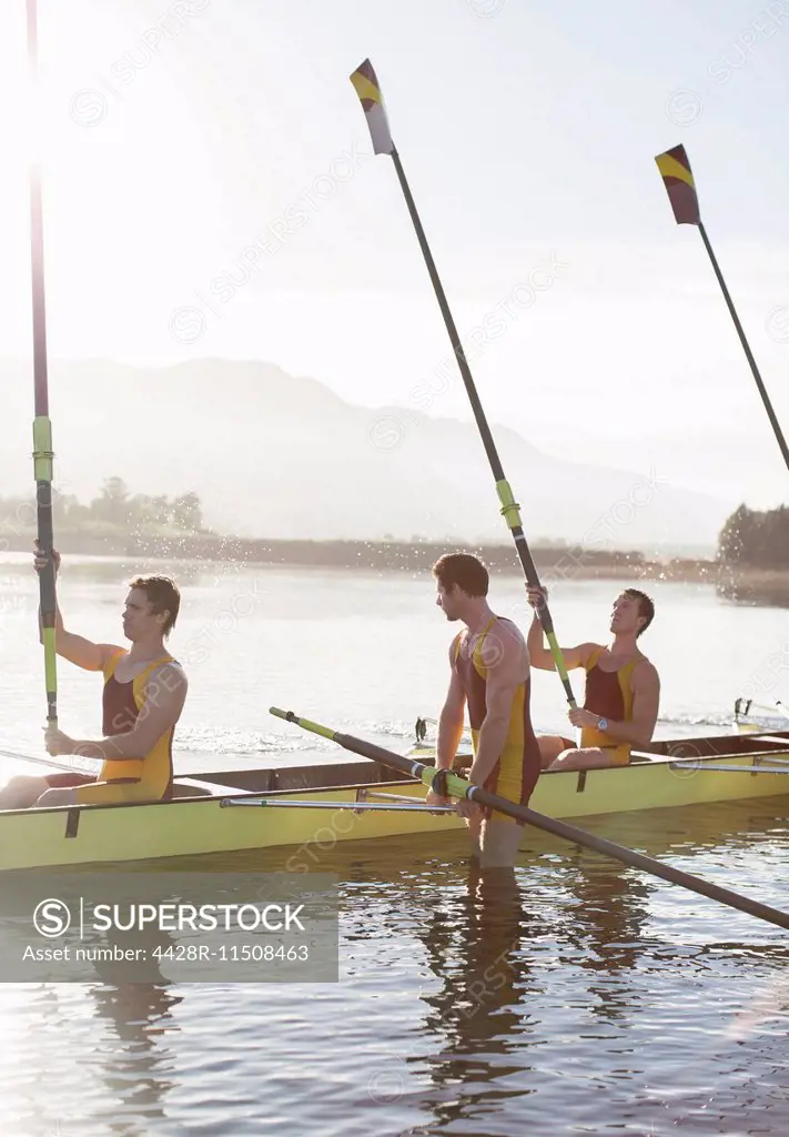 Rowing team lifting oars in lake