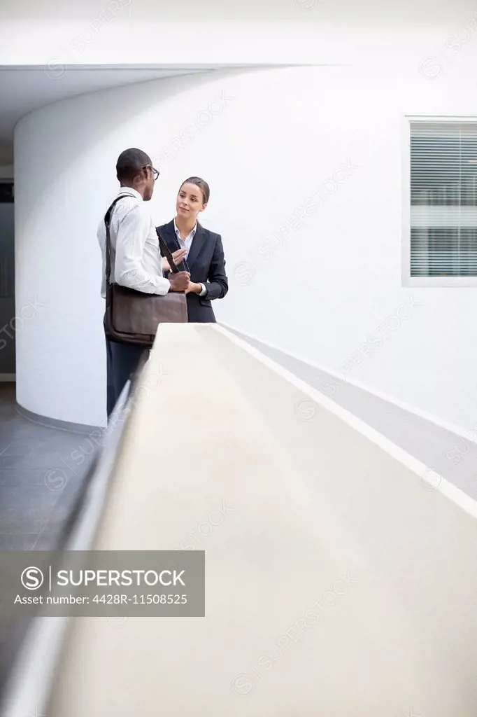 Businessman and businesswoman talking in office corridor