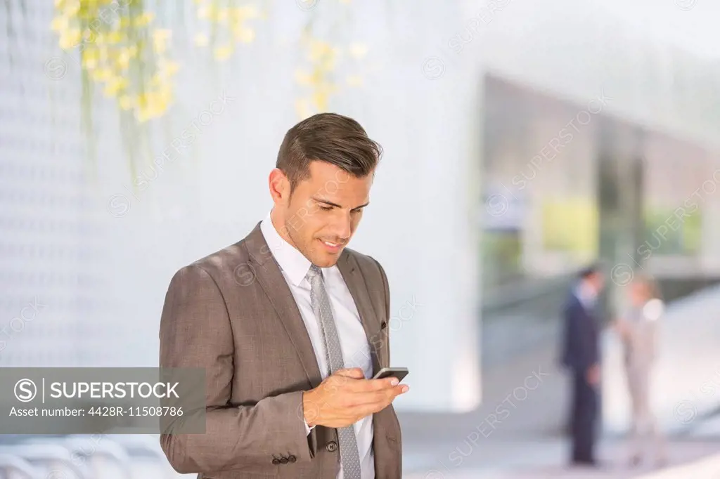 Businessman texting with cell phone outdoors