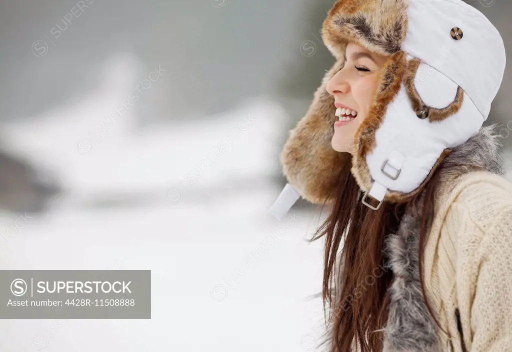 Happy woman wearing fur hat in snow