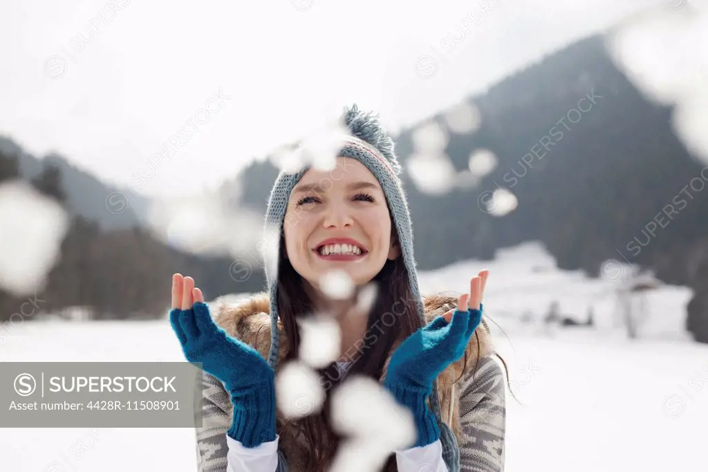 Happy woman enjoying falling snow in field