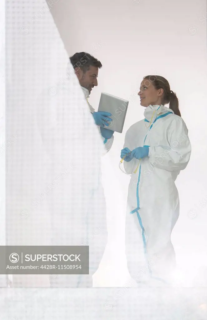 Scientists in clean suits with digital tablet