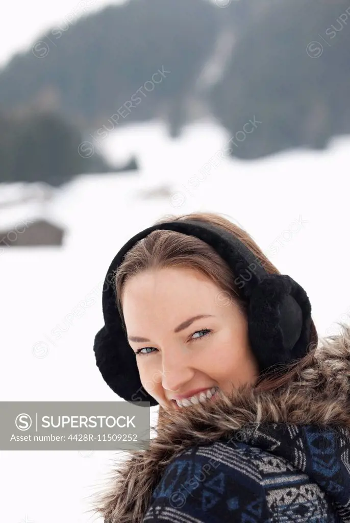 Close up portrait of woman wearing earmuffs in snowy field