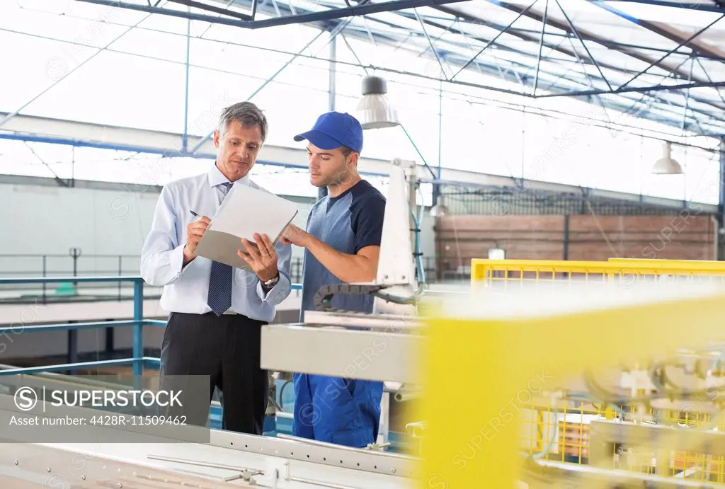 Supervisor and worker with clipboard in food processing plant
