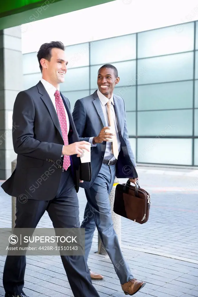 Smiling businessmen walking with coffee