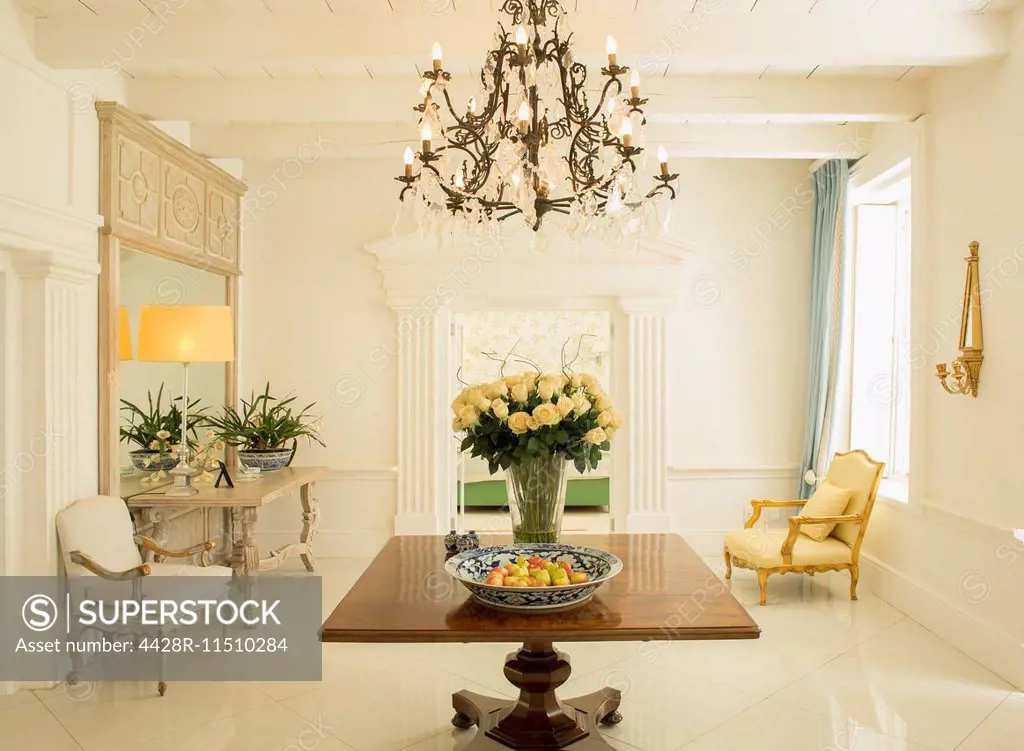 Chandelier over rose bouquet on table in luxury foyer