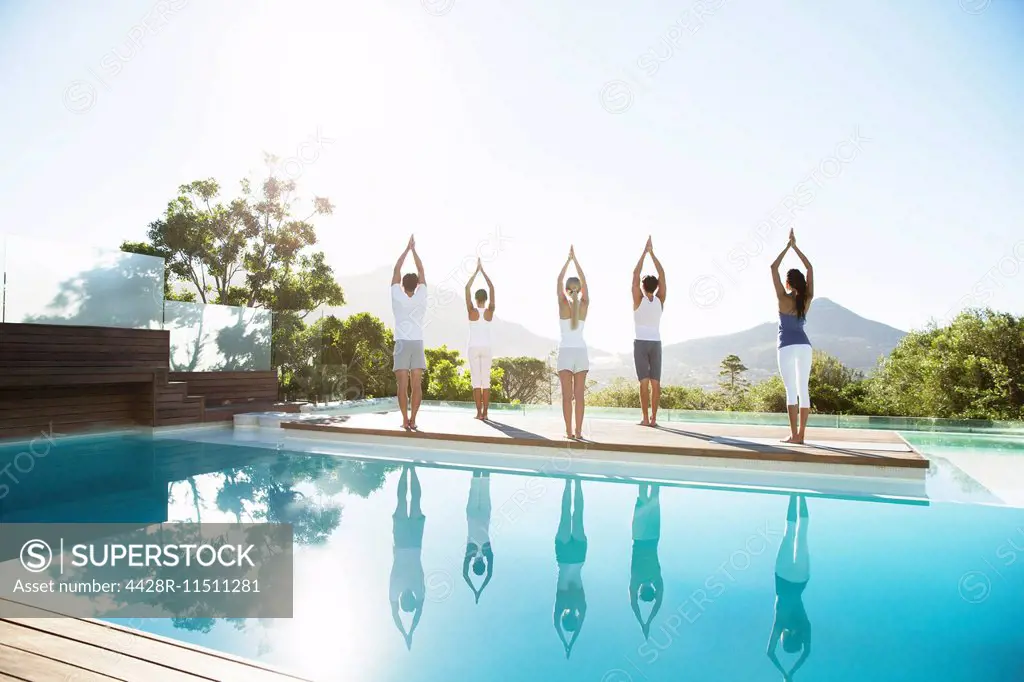 People practicing yoga at poolside