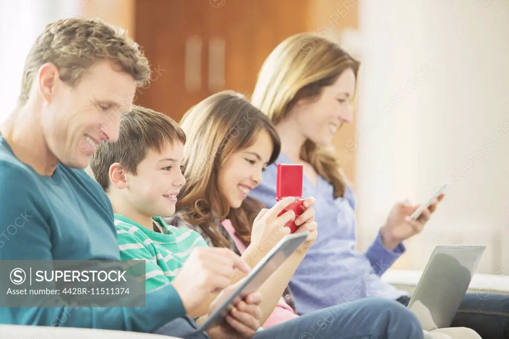 Family using technology on sofa