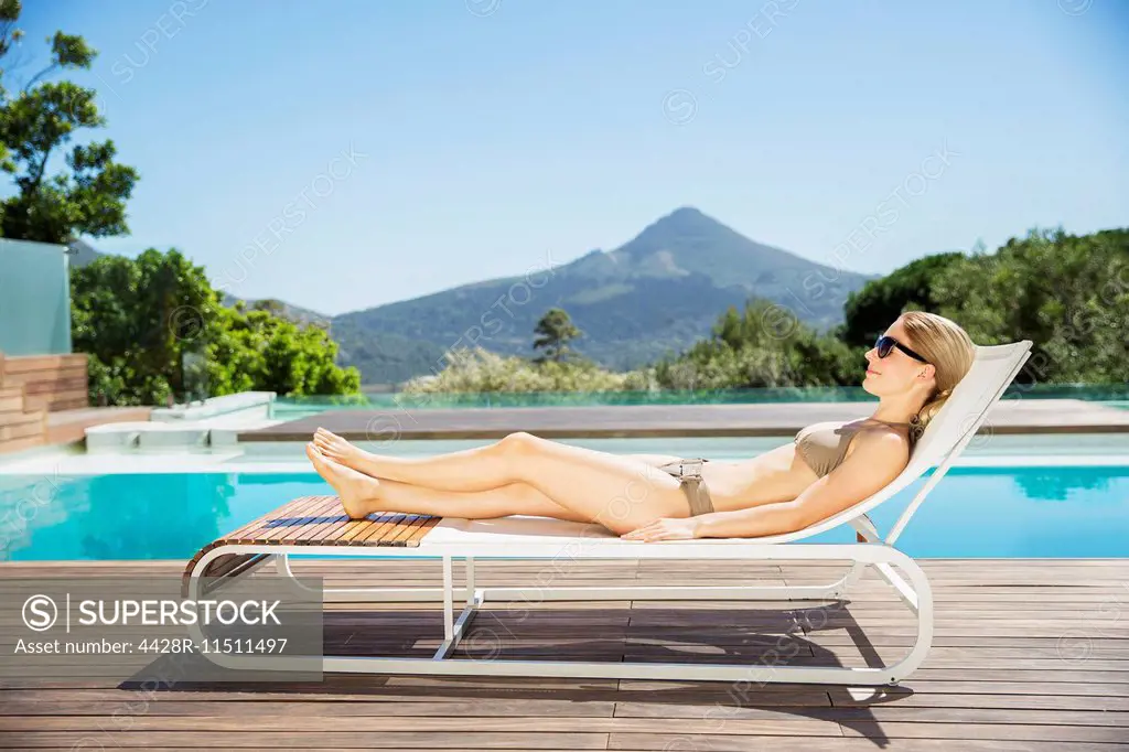 Woman relaxing on lounge chair at poolside