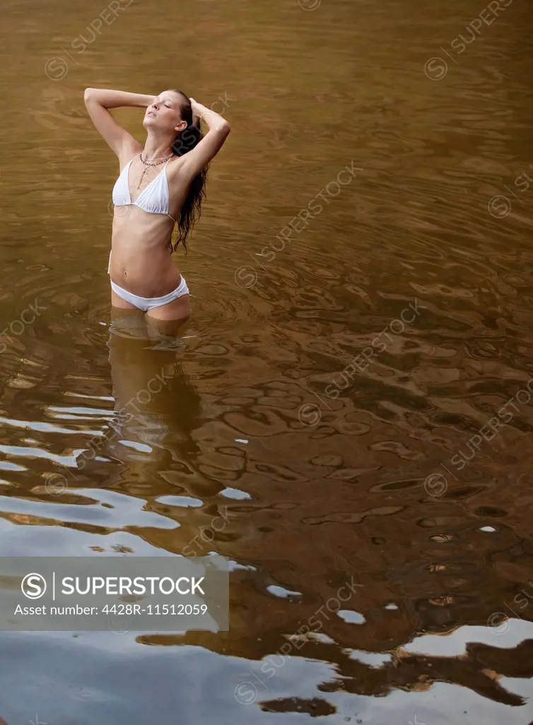 Woman standing with hands in hair in river