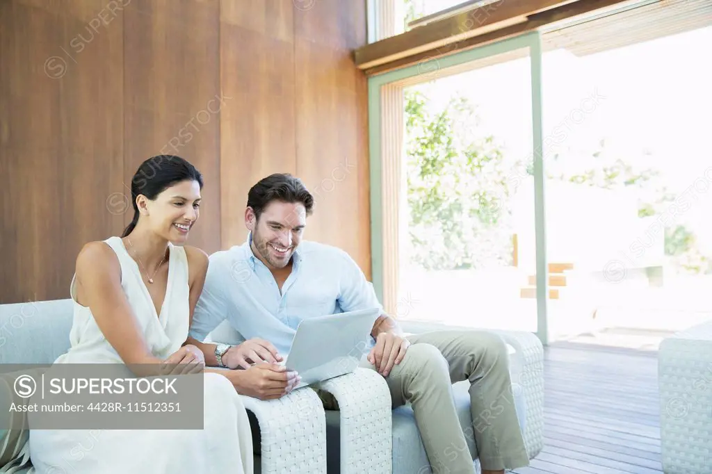 Couple using laptop on armchairs