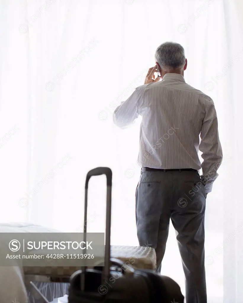 Businessman talking on cell phone in hotel room
