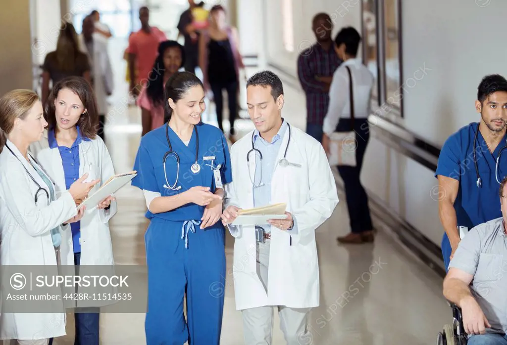 Doctor and nurse reading medical chart in hospital hallway