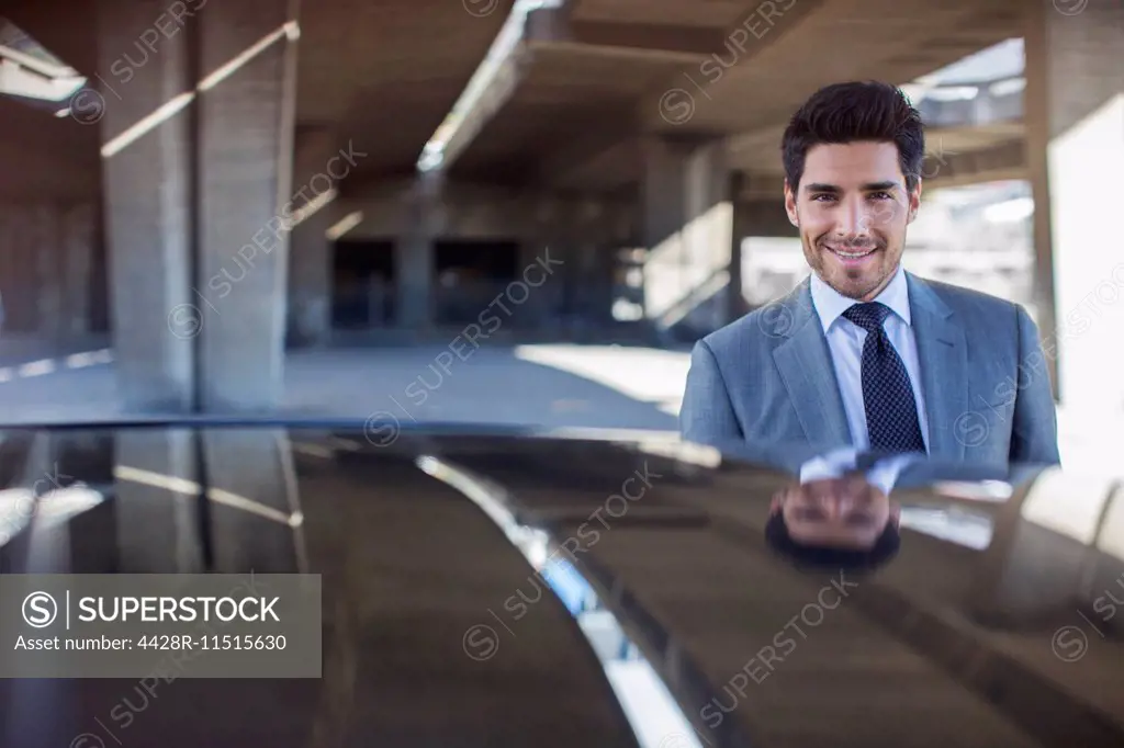 Businessman standing near car in parking garage