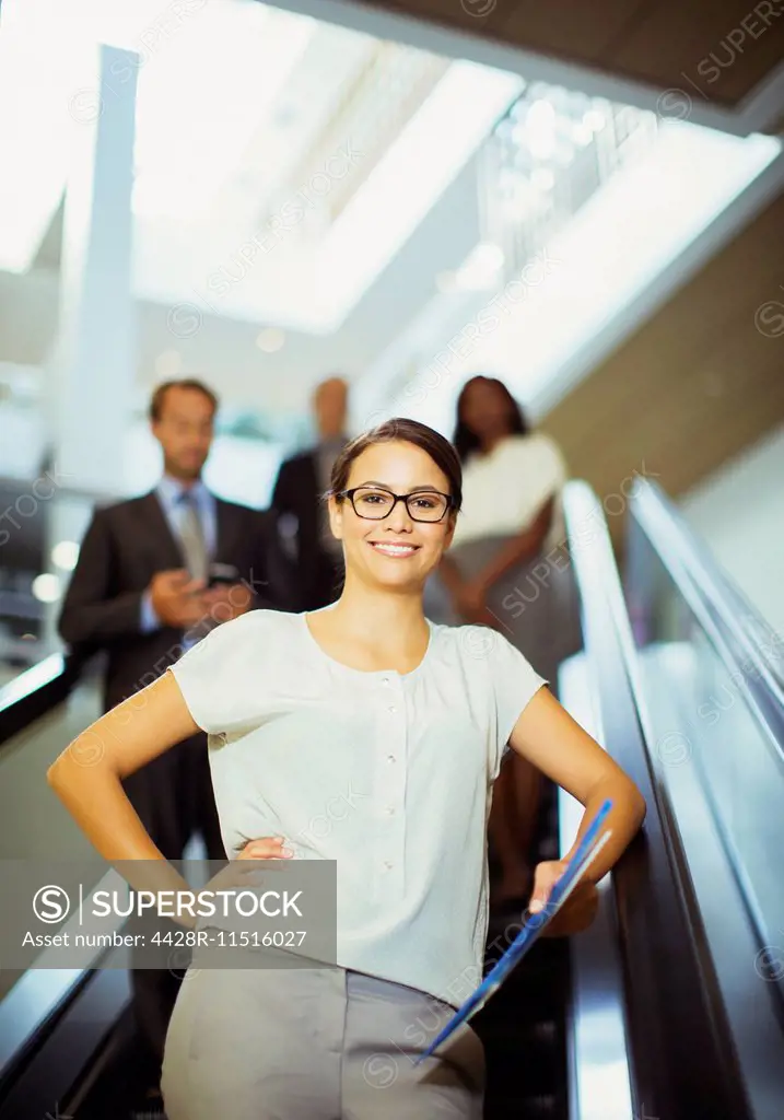 Businesswoman riding escalator in office building