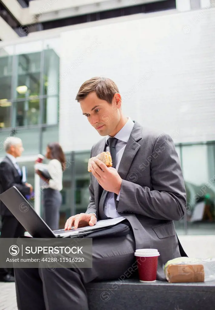 Businessman eat lunch and working outside office building