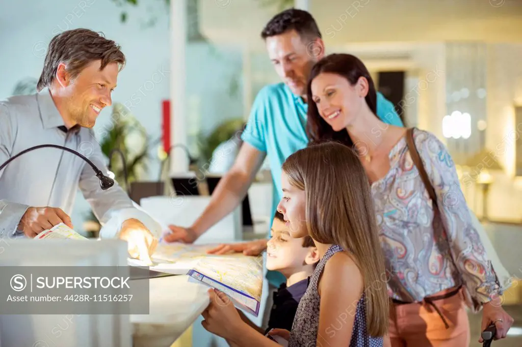 Family with two children at reception desk in hotel lobby